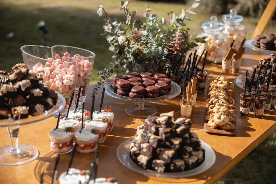 Mesa dulce al aire libre con brownies, vasitos y nubes