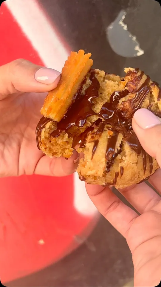 Cookie de churros con chocolate partida con las manos